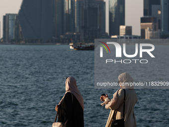 Women wearing traditional dress are seen with the city and Doha Bay in Doha, Qatar on December 3, 2024. (