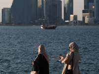 Women wearing traditional dress are seen with the city and Doha Bay in Doha, Qatar on December 3, 2024. (