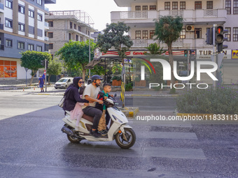 A family of three rides on a moped by the main street of the city in Alanya, Antalya, Turkey, on November 3, 2024. (