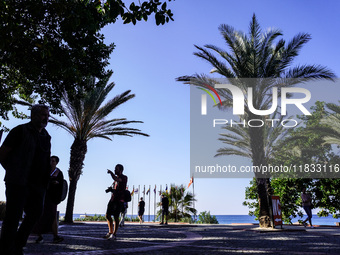 People talk in front of the sea coast with palm trees in the background in Alanya, Antalya, Turkey, on November 5, 2024 (