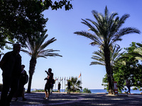 People talk in front of the sea coast with palm trees in the background in Alanya, Antalya, Turkey, on November 5, 2024 (