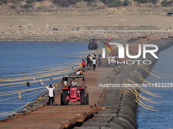 Labourers build a floating pontoon bridge at Sangam, the confluence of the rivers Ganges, Yamuna, and Saraswati, in Prayagraj, India, on Dec...