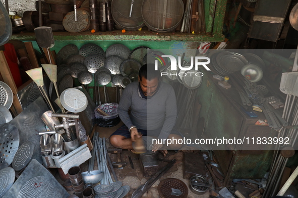 A worker molds an aluminum plate with a hammer to make utensils at an aluminum utensils manufacturing unit in Kolkata, India, on December 4,...