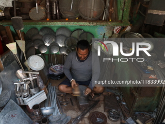 A worker molds an aluminum plate with a hammer to make utensils at an aluminum utensils manufacturing unit in Kolkata, India, on December 4,...