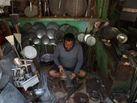 A worker molds an aluminum plate with a hammer to make utensils at an aluminum utensils manufacturing unit in Kolkata, India, on December 4,...