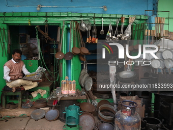 A vendor waits for his customers in his aluminum and iron utensils shop in Kolkata, India, on December 4, 2024. (