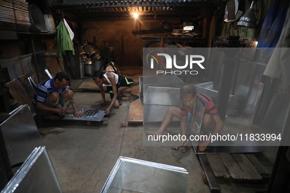 Workers mold aluminum plates with a hammer to make utensils at an aluminum utensils manufacturing unit in Kolkata, India, on December 4, 202...