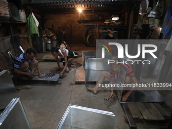 Workers mold aluminum plates with a hammer to make utensils at an aluminum utensils manufacturing unit in Kolkata, India, on December 4, 202...