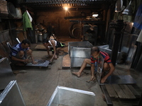 Workers mold aluminum plates with a hammer to make utensils at an aluminum utensils manufacturing unit in Kolkata, India, on December 4, 202...