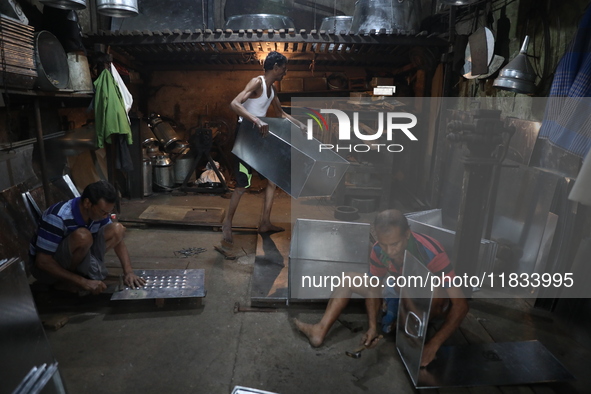 Workers mold aluminum plates with a hammer to make utensils at an aluminum utensils manufacturing unit in Kolkata, India, on December 4, 202...