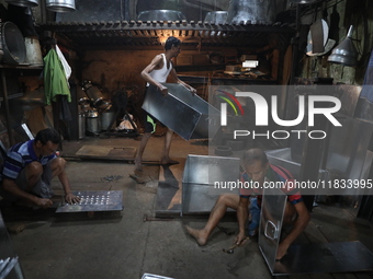 Workers mold aluminum plates with a hammer to make utensils at an aluminum utensils manufacturing unit in Kolkata, India, on December 4, 202...