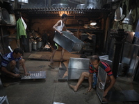 Workers mold aluminum plates with a hammer to make utensils at an aluminum utensils manufacturing unit in Kolkata, India, on December 4, 202...