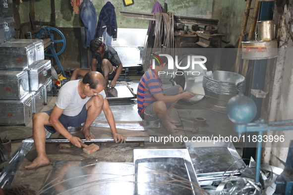 Workers mold aluminum plates with a hammer to make utensils at an aluminum utensils manufacturing unit in Kolkata, India, on December 4, 202...