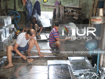 Workers mold aluminum plates with a hammer to make utensils at an aluminum utensils manufacturing unit in Kolkata, India, on December 4, 202...