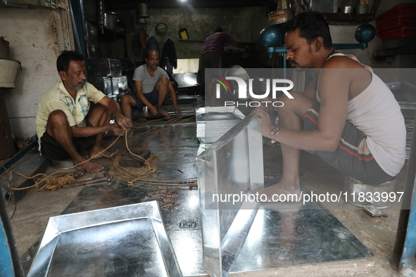 Workers mold aluminum plates with a hammer to make utensils at an aluminum utensils manufacturing unit in Kolkata, India, on December 4, 202...