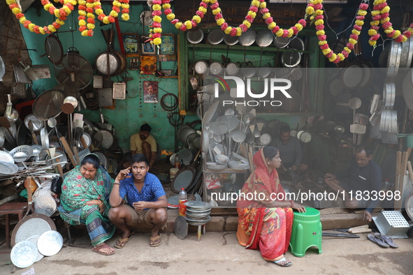 A woman sits in front of an aluminum utensils manufacturing unit in Kolkata, India, on December 4, 2024. 