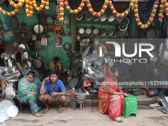 A woman sits in front of an aluminum utensils manufacturing unit in Kolkata, India, on December 4, 2024. (