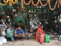 A woman sits in front of an aluminum utensils manufacturing unit in Kolkata, India, on December 4, 2024. (