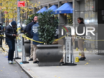 NYPD police mark evidence found at the scene with evidence markers as CEO of UnitedHealthcare Brian Thompson, 50, is shot and killed as he e...