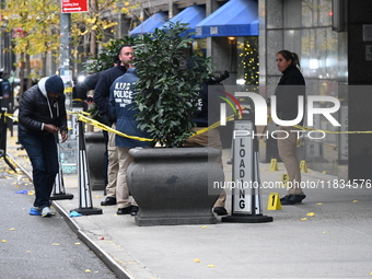 NYPD police mark evidence found at the scene with evidence markers as CEO of UnitedHealthcare Brian Thompson, 50, is shot and killed as he e...