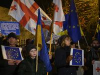 People hold placards as they wave Ukrainian, Georgian, and European Union flags during a rally outside the embassy of Georgia in Warsaw, Pol...