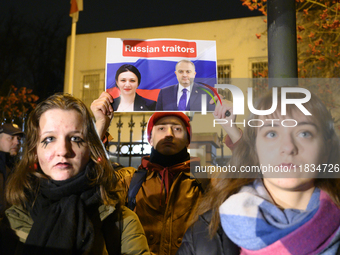 A demonstrator holds a sign depicting members of the Georgian Dream party on a Russian flag as the background during a rally outside the emb...