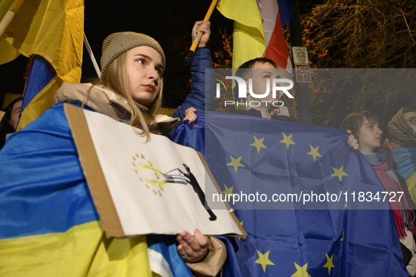 People hold placards as they wave Ukrainian, Georgian, and European Union flags during a rally outside the embassy of Georgia in Warsaw, Pol...