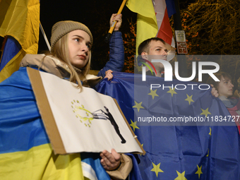 People hold placards as they wave Ukrainian, Georgian, and European Union flags during a rally outside the embassy of Georgia in Warsaw, Pol...