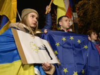 People hold placards as they wave Ukrainian, Georgian, and European Union flags during a rally outside the embassy of Georgia in Warsaw, Pol...