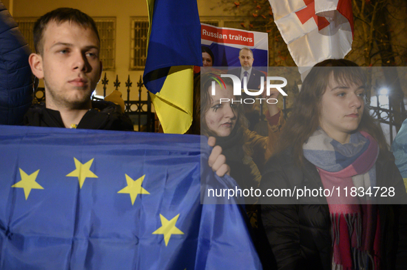 People hold placards as they wave Ukrainian, Georgian, and European Union flags during a rally outside the embassy of Georgia in Warsaw, Pol...