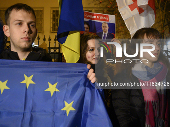 People hold placards as they wave Ukrainian, Georgian, and European Union flags during a rally outside the embassy of Georgia in Warsaw, Pol...