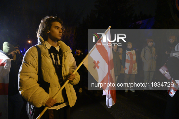 A demonstrator holds a national flag of Georgia during a rally outside the embassy of Georgia in Warsaw, Poland, on December 4, 2024. Dozens...