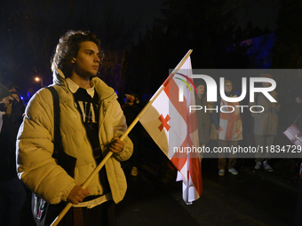 A demonstrator holds a national flag of Georgia during a rally outside the embassy of Georgia in Warsaw, Poland, on December 4, 2024. Dozens...