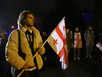 A demonstrator holds a national flag of Georgia during a rally outside the embassy of Georgia in Warsaw, Poland, on December 4, 2024. Dozens...