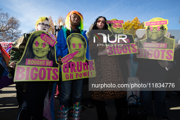 People with signs accusing Supreme Court justices of misconduct take part in a demonstration outside the Court as it hears a case on gender-...