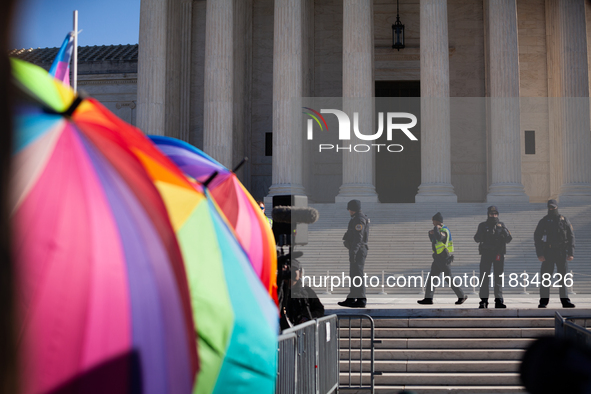 Supreme Court Police patrol the plaza in front of the Court while demonstrators with rainbow umbrellas shield supporters of transgender care...