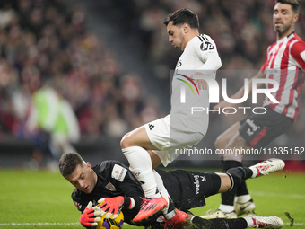 Brahim Diaz attacking midfield of Real Madrid and Spain and Julen Agirrezabala goalkeeper of Athletic Club and Spain compete for the ball du...