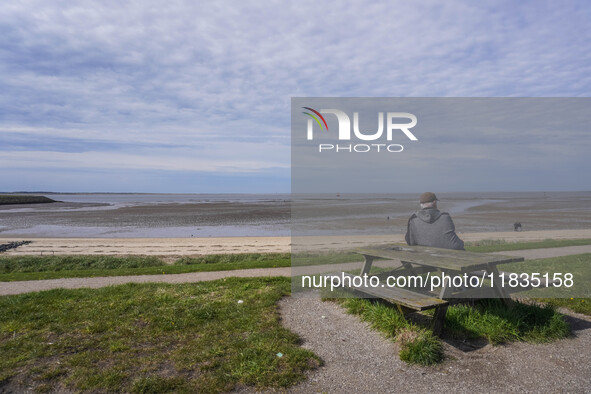 A man sits on a bench on the shore of the Wadden Sea, looking at the ebb of the tide in Esbjerg, Jutland, Denmark, on April 28, 2024. 