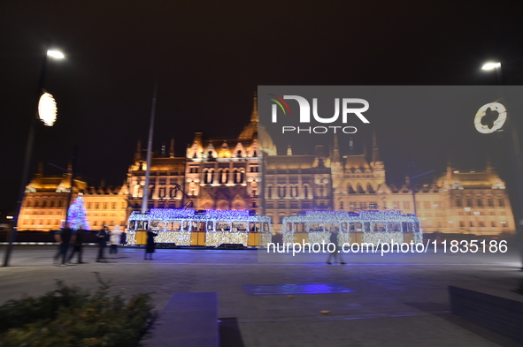 A tram decorated with Christmas lights passes in front of the Hungarian Parliament in Budapest, Hungary, on December 4, 2024. 