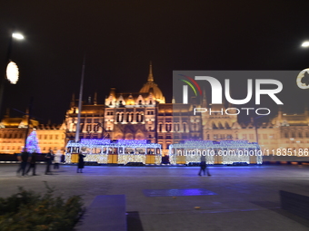 A tram decorated with Christmas lights passes in front of the Hungarian Parliament in Budapest, Hungary, on December 4, 2024. (