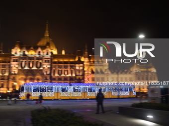 A tram decorated with Christmas lights passes in front of the Hungarian Parliament in Budapest, Hungary, on December 3, 2024.(