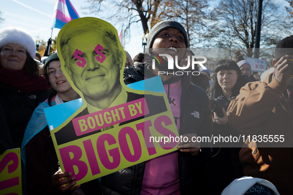 A demonstrator displays a sign accusing Supreme Court Justice Neil Gorsuch of corruption during a rally in support of gender-affirming care...