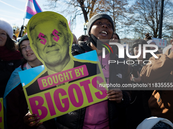 A demonstrator displays a sign accusing Supreme Court Justice Neil Gorsuch of corruption during a rally in support of gender-affirming care...