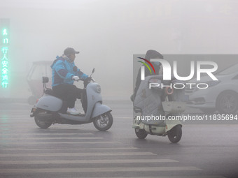 Citizens ride in heavy fog with visibility of less than 100 meters on a street in Hua County, Anyang, China, on December 5, 2024. (