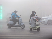 Citizens ride in heavy fog with visibility of less than 100 meters on a street in Hua County, Anyang, China, on December 5, 2024. (