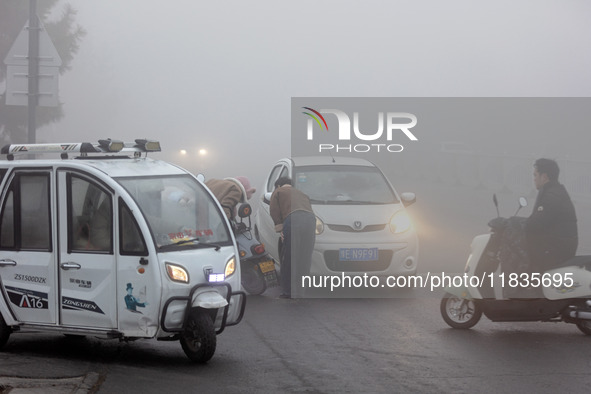 Citizens ride in heavy fog with visibility of less than 100 meters on a street in Hua County, Anyang, China, on December 5, 2024. 