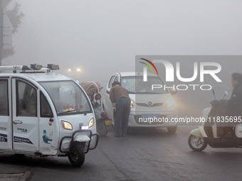 Citizens ride in heavy fog with visibility of less than 100 meters on a street in Hua County, Anyang, China, on December 5, 2024. (