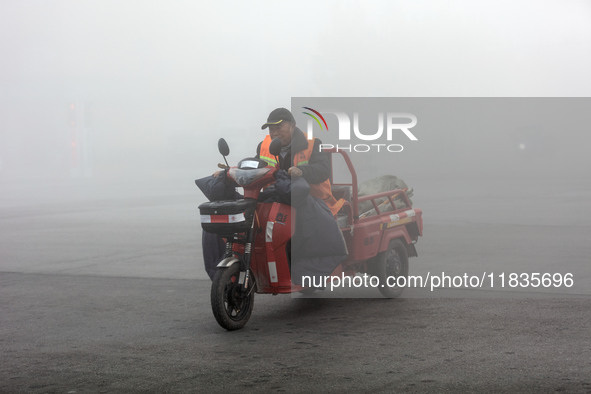 Citizens ride in heavy fog with visibility of less than 100 meters on a street in Hua County, Anyang, China, on December 5, 2024. 