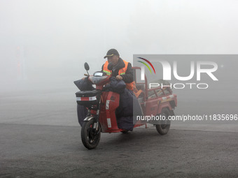 Citizens ride in heavy fog with visibility of less than 100 meters on a street in Hua County, Anyang, China, on December 5, 2024. (