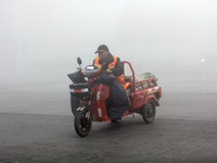 Citizens ride in heavy fog with visibility of less than 100 meters on a street in Hua County, Anyang, China, on December 5, 2024. (